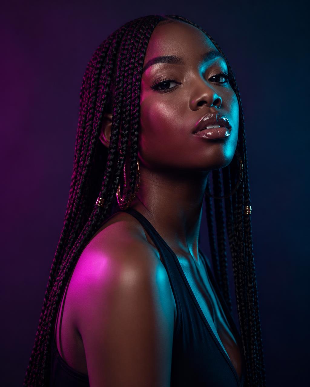 Long neat box braids under magenta and teal studio light